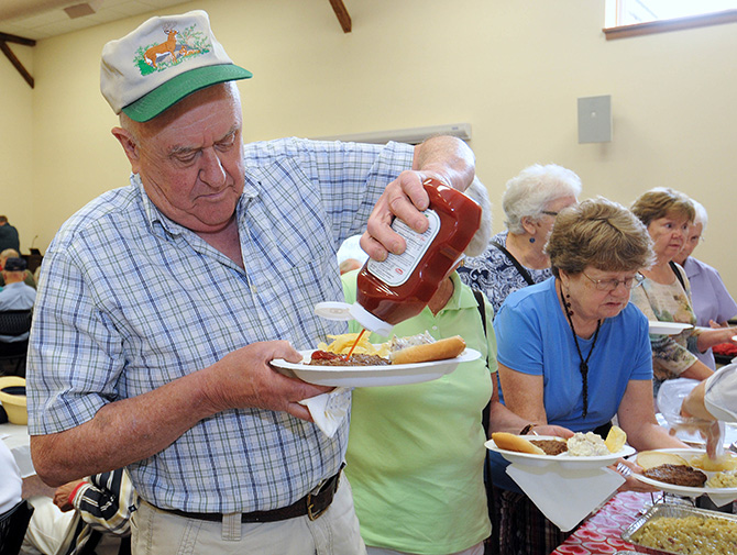 Dave Casic of Canterbury topped off his burger while enjoying a BBQ Social at the Centennial Senior Center.